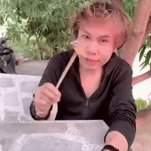 a young man is sitting at a table eating food with a toothpick .