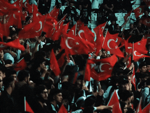 a crowd of people holding up red flags with the letter o on it