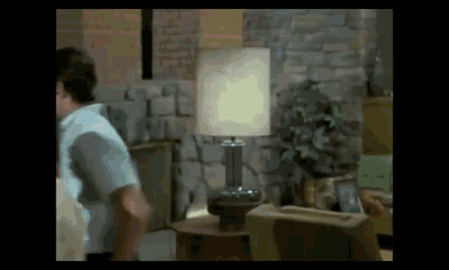 a man standing in a living room with a lamp