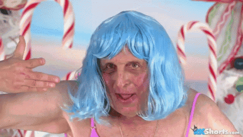 a man wearing a blue wig and a pink bikini is standing in front of candy canes ..