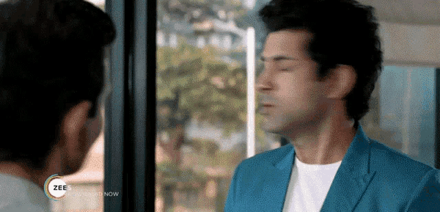 a man in a blue jacket is standing in front of a window .