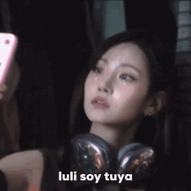 a woman wearing headphones is taking a picture of herself with her phone .