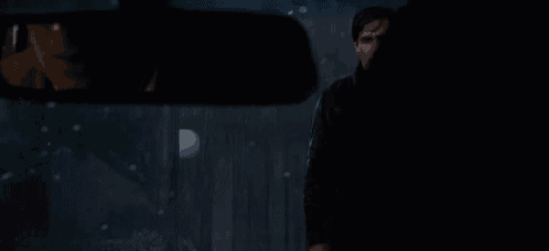 a man is standing in front of a fence in the rain .