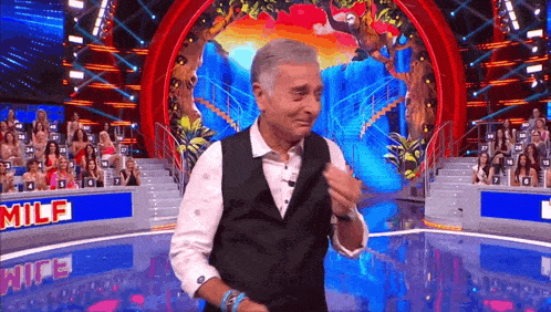 a man is dancing on a stage with a sign that says milf in the background