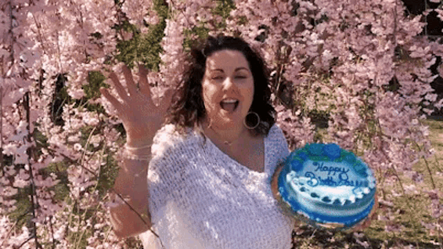 a woman holds a blue cake that says happy birthday