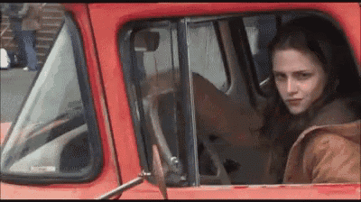 a woman is sitting in the back of a red truck looking out the window .