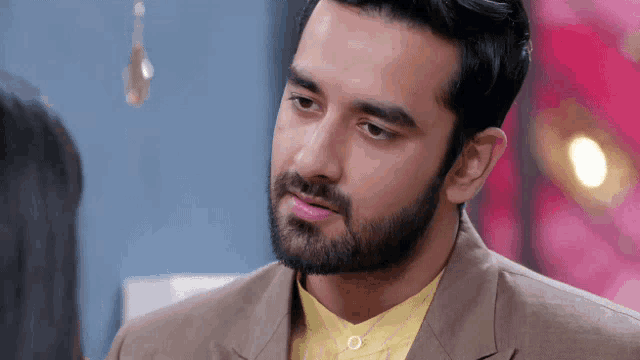 a man with a beard and a yellow shirt is looking at a woman .