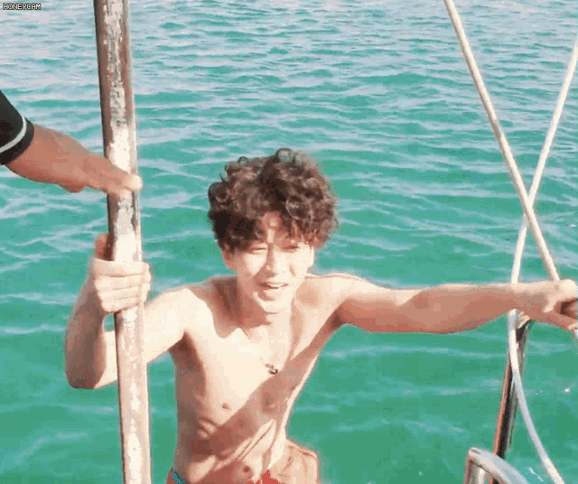 a shirtless man is holding a pole in the water