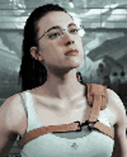 a woman wearing glasses and a harness on her shoulder is standing in a room .