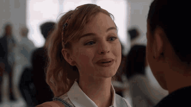 a woman in a white shirt and blue vest is smiling