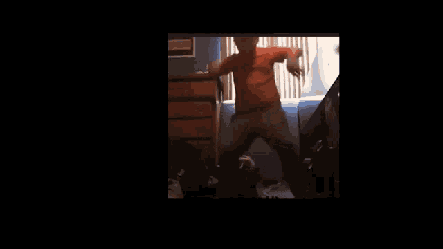 a man in a red shirt is dancing in a dark room