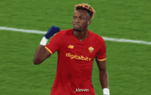 a soccer player wears a red jersey with digitalbits on the front