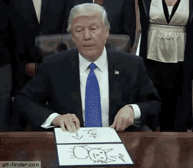 a man in a suit and tie is sitting at a table with a drawing of a sun on it