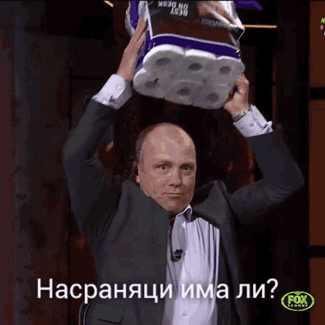a man in a suit is holding a roll of toilet paper over his head with a fox league logo in the corner