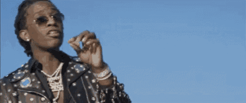 a man wearing sunglasses is smoking a cigarette and blowing a kiss .