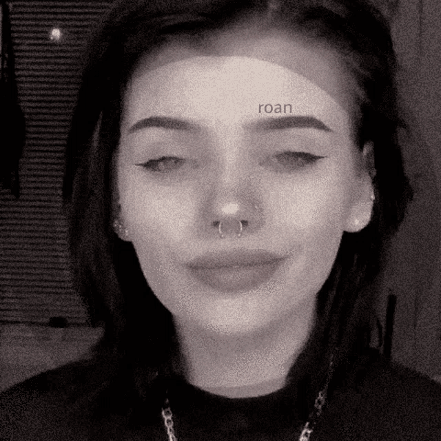 a black and white photo of a girl with a nose ring and earrings .