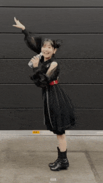 a girl in a black dress is holding a bottle of water in her hand