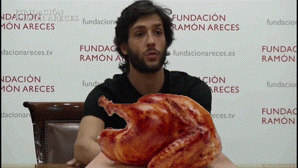 a man holding a turkey in front of a fundacion ramon areces wall