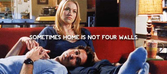 a man and a woman laying on a red couch with the words sometimes home is not four walls