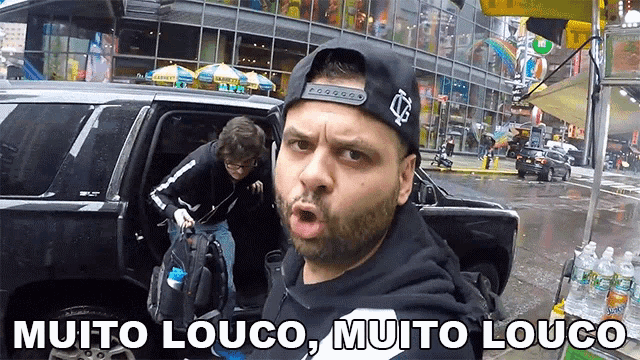 a man in a baseball cap is standing in front of a car with the words " muito louco muito louco " below him