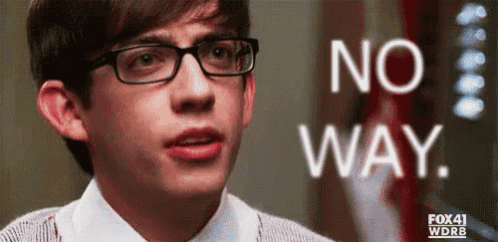 a young man wearing glasses is standing in front of a sign that says no way