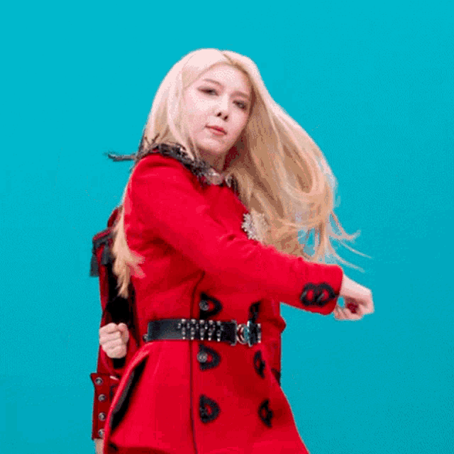 a woman in a red coat with a black belt is dancing