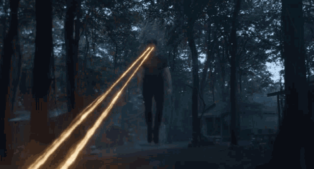 a person is standing in the woods with a beam of light coming from behind them