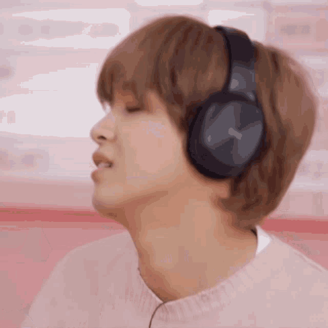 a young man wearing headphones is listening to music and singing .