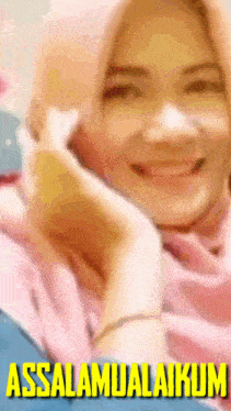 a woman wearing a pink hijab is smiling and has the words assalamualaikum written below her