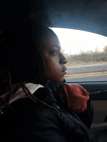 a woman with dreadlocks is looking out of a window
