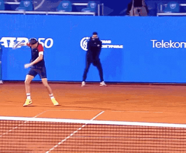 a man is playing tennis in front of a blue wall that says telekom on it