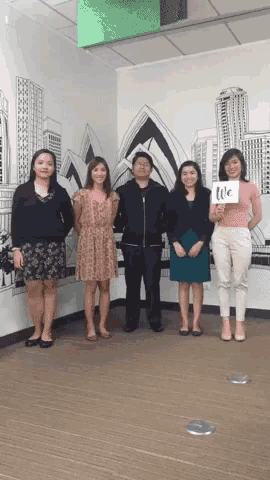 a group of people standing in front of a wall with a picture of sydney on it