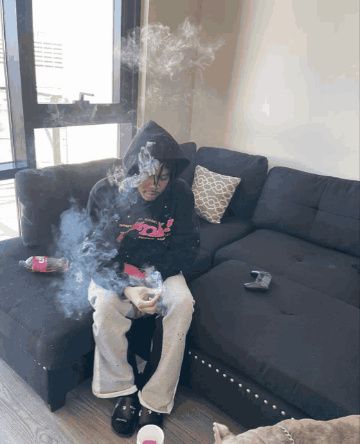 a person sitting on a couch smoking a cigarette and wearing a pink panther sweatshirt