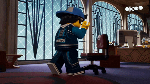 a lego man wearing a monsters shirt is standing in an office