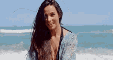 a woman with long hair is smiling at the beach