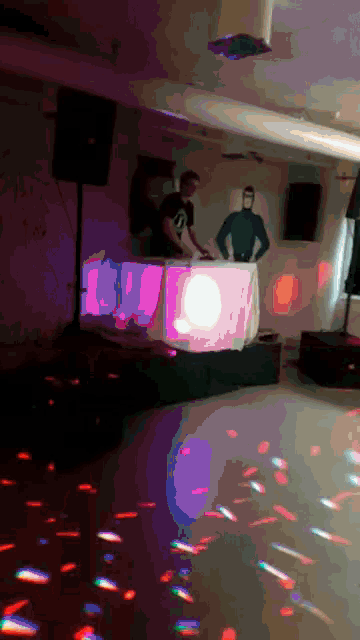 a man in a blue shirt is playing a dj set at a party