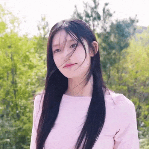 a young woman with long black hair is wearing a pink shirt .