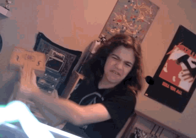 a metallica poster hangs on a wall behind a person