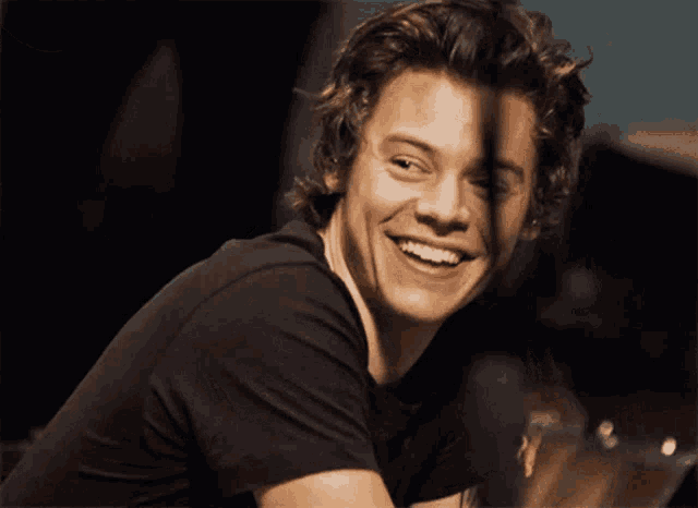 a man with a tattoo on his arm is smiling and wearing a black shirt