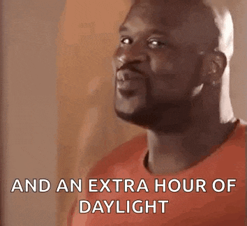 a man in a red shirt is standing in front of a wall and saying `` and an extra hour of daylight '' .