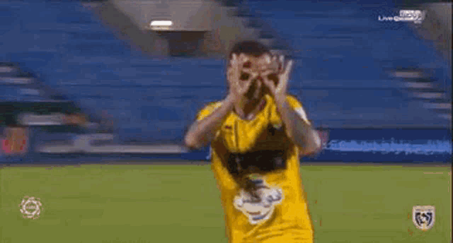 a man in a yellow shirt is blowing a kiss while standing on a field .