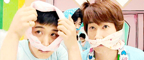 a man with a bandage around his mouth looks at the camera while another man looks on