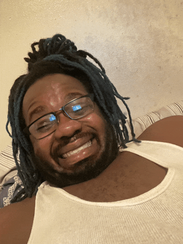 a man with blue hair and glasses is smiling for the camera