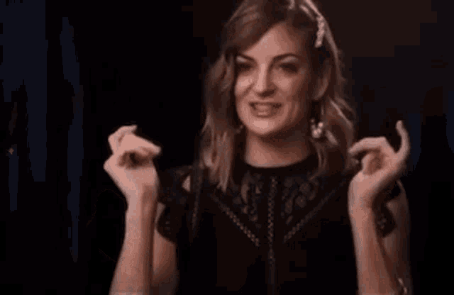 a woman in a black dress is making a funny face while dancing in a dark room .