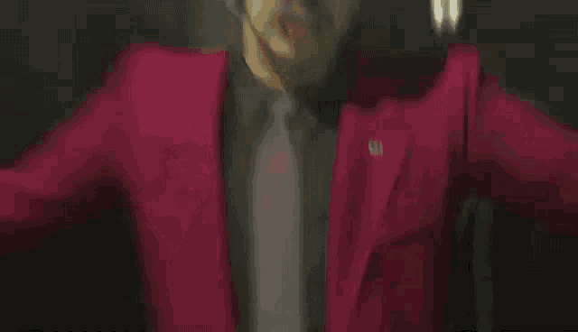 a man in a pink suit is standing in front of a fence .