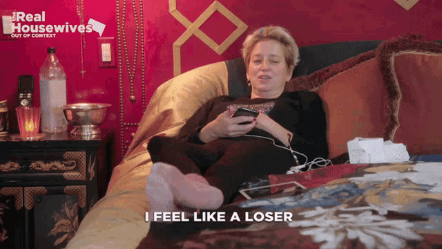 a woman is laying on a bed with a real housewives logo behind her