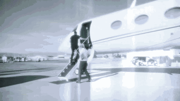 a black and white photo of two people boarding a private jet