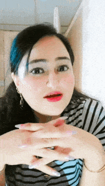 a woman with long nails and a striped shirt is making a funny face
