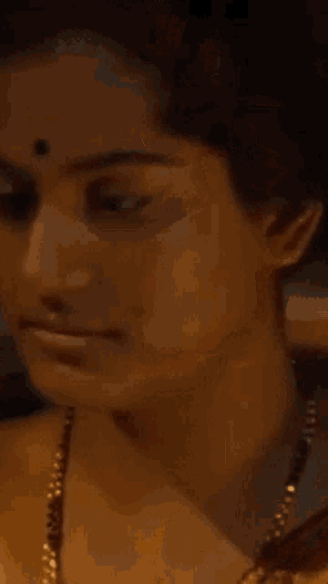 a close up of a woman 's face with a gold chain around her neck