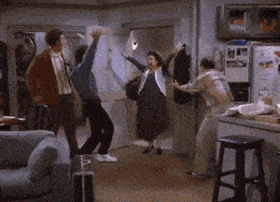 a group of people are dancing in a living room with their arms in the air .
